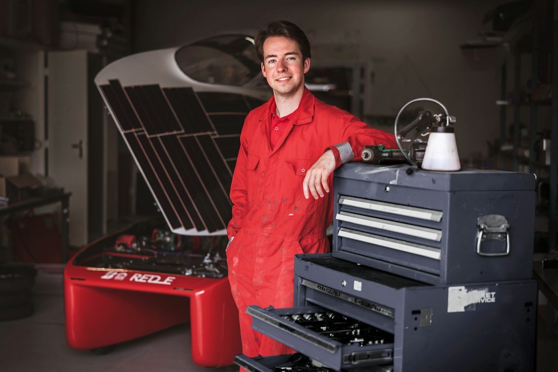 A technician in red overalls beside a tool chest