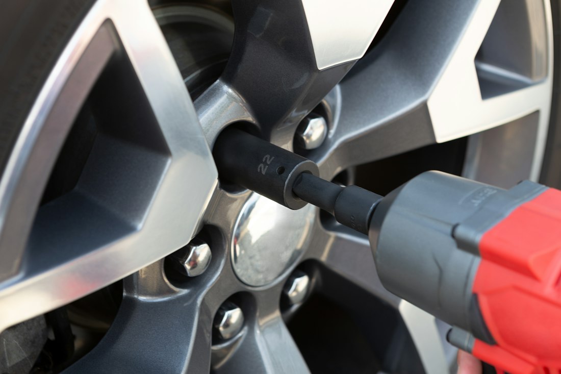 An impact driver removing a wheel bolt from an alloy wheel